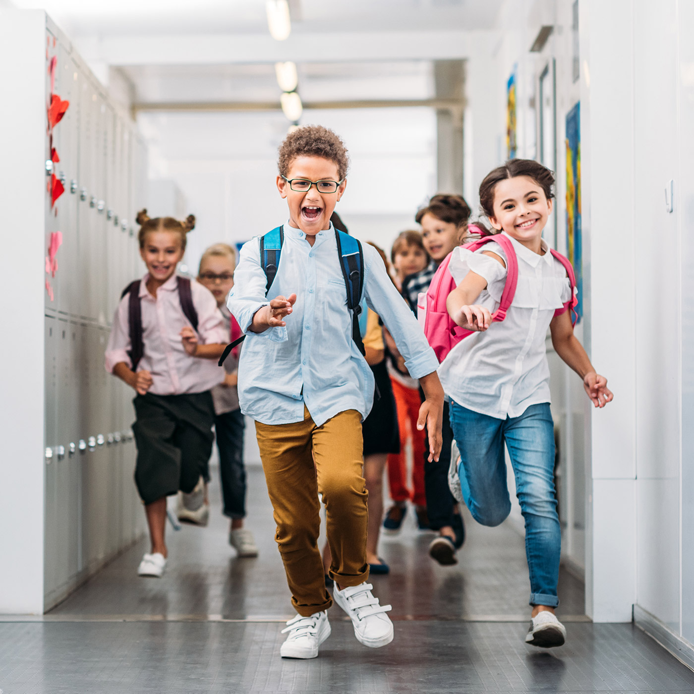 Children in a private school excitedly running through a hallway
